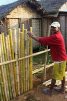 Een man bouwt een hek van bamboe om zijn huis